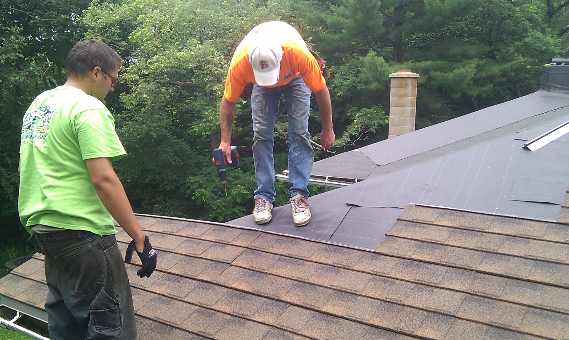 Hammer It roofers installing ridge flashing on a shingle roof